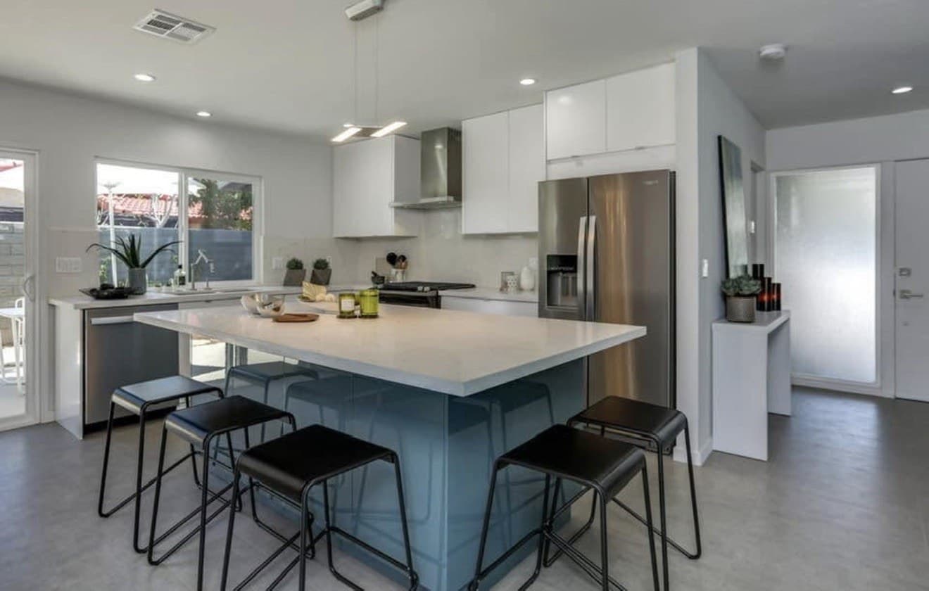 Kitchen with a blue-gray island, seen from the living side