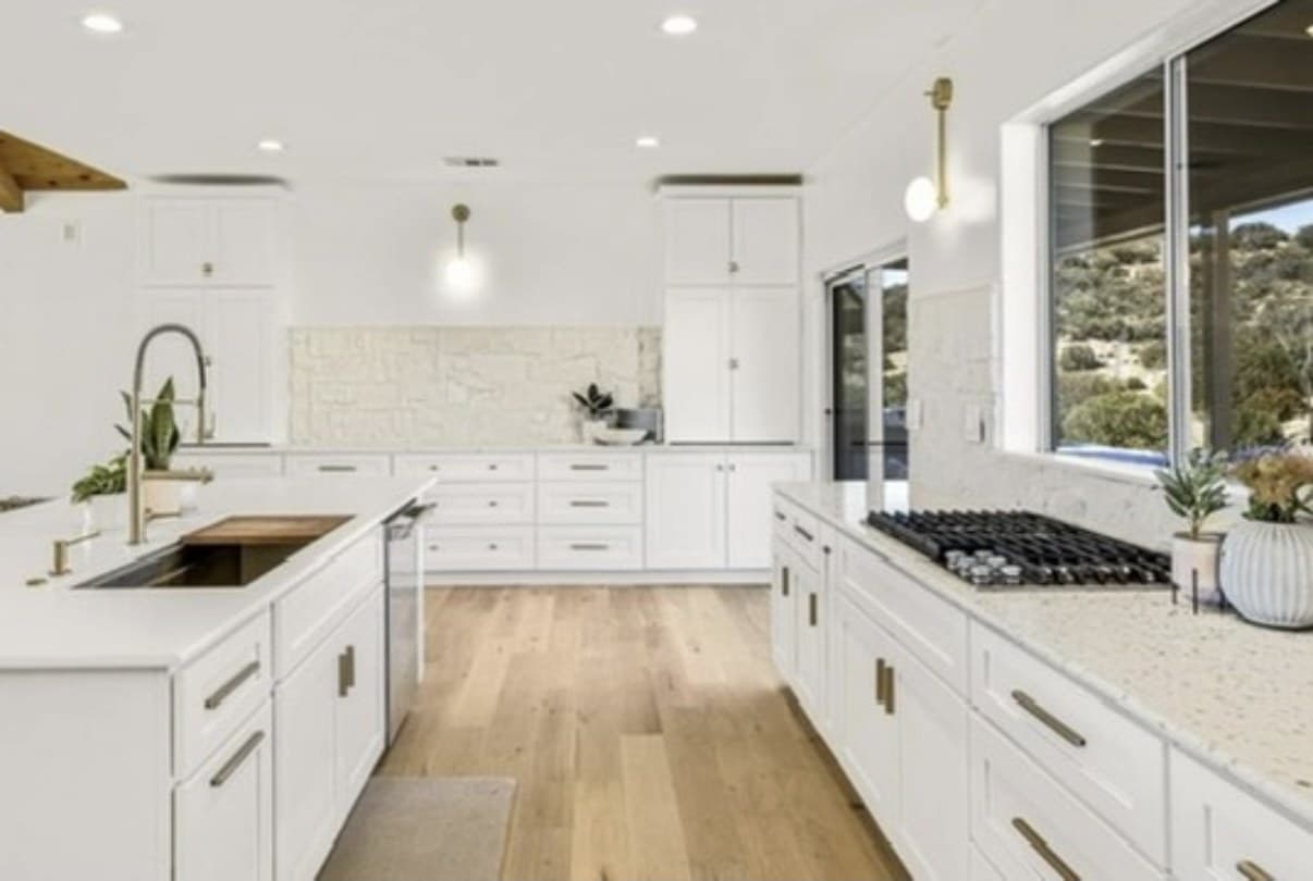 White kitchen with a long island, cooktop, and hill view