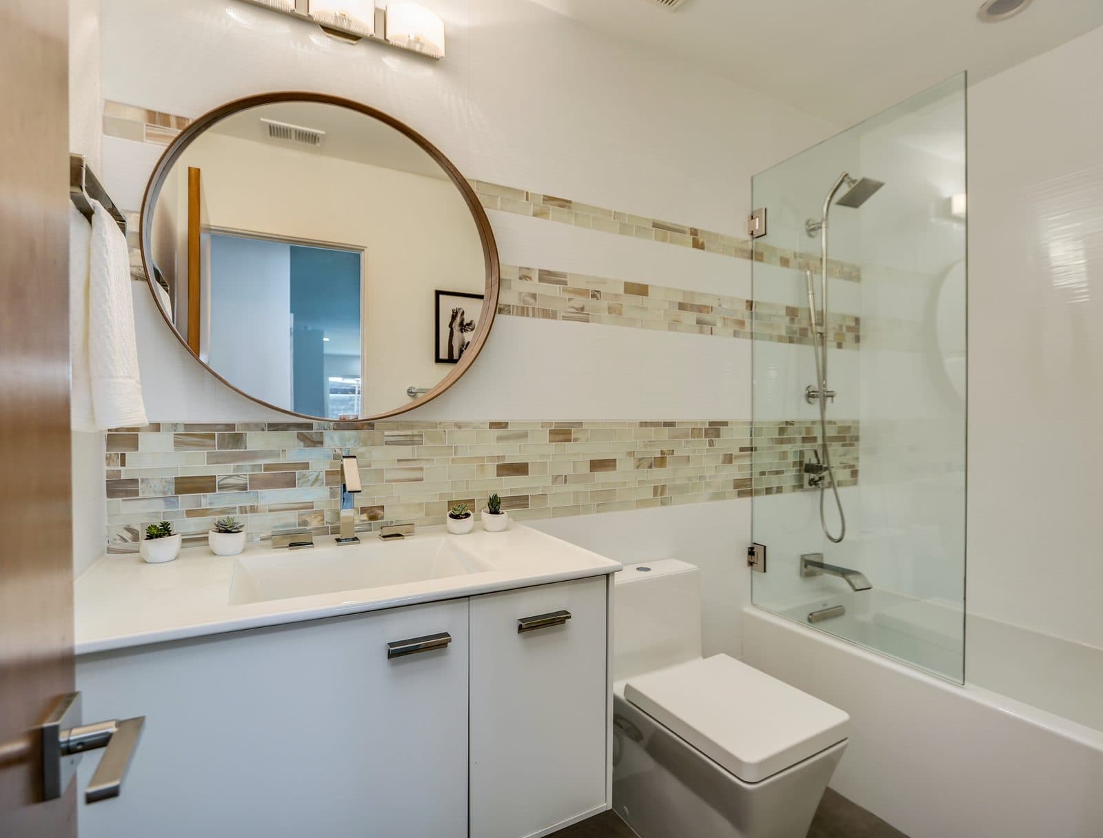 MJ Remodel job photo of a modern bathroom remodel: walk-in frameless glass shower, floating white vanity, and a backlit mirror