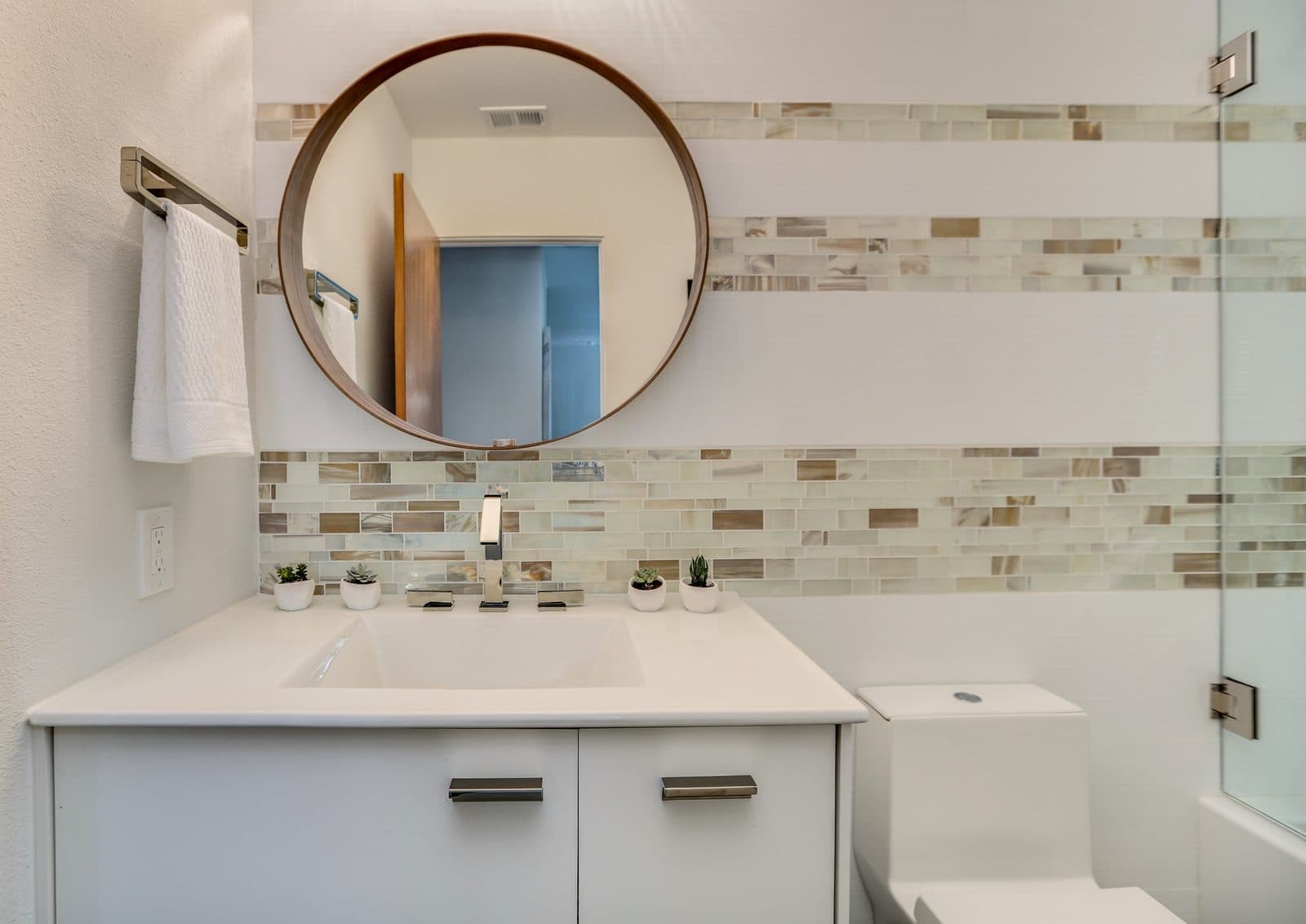 MJ Remodel job photo of a modern bathroom remodel: floating white vanity with a round backlit mirror, seen straight on
