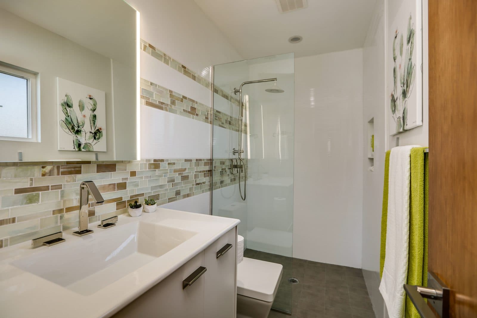 MJ Remodel job photo of a modern bathroom remodel: close-up of a chrome faucet and a glass-and-stone mosaic tile band
