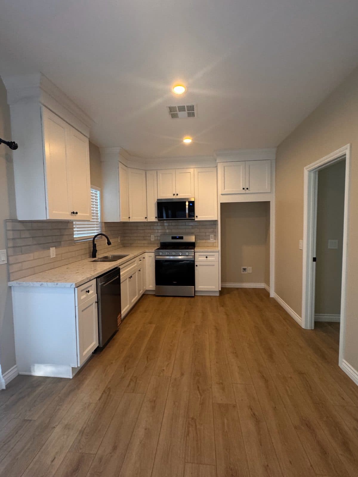 MJ Remodel job photo from an ADU completed in Redlands, CA: finished L-shaped kitchen with white cabinets and stainless appliances
