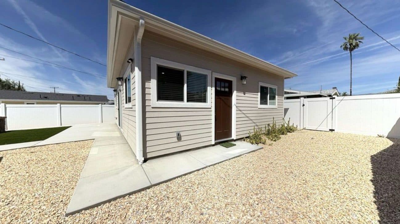 MJ Remodel job photo from an ADU completed in Redlands, CA: front exterior with a door, gravel yard, and white fence